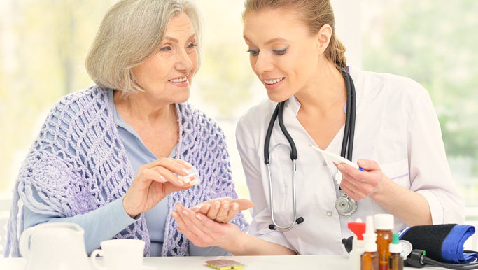 happy senior woman and nurse holding medical kits