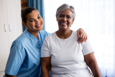 Portrait of young nurse with senior patient in nursing home